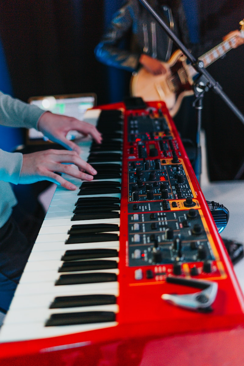 person playing red and black electric keyboard