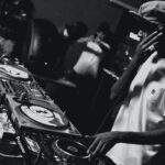 grayscale photo of man playing DJ mixing console