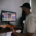 a man sitting in front of a computer playing a guitar