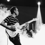 man playing guitar on stage with smoke