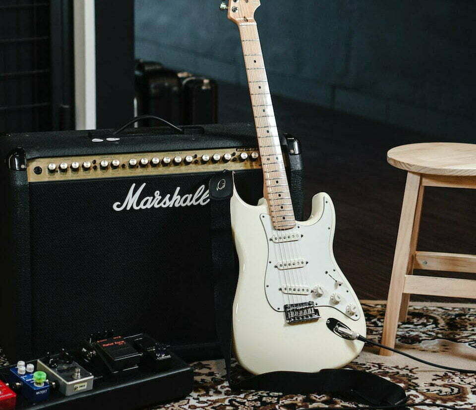 white and black stratocaster electric guitar on black guitar amplifier